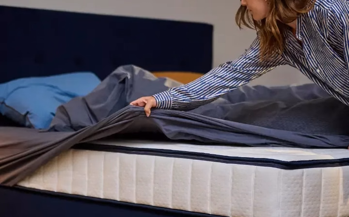 Vrouw die haar Auping bed opmaakt